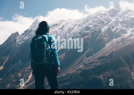 Femme avec sac à dos à la recherche de belles montagnes dans les nuages au lever du soleil. Paysage avec girl, de hautes roches avec des sommets enneigés, ciel bleu avec des nuages en Pen Banque D'Images