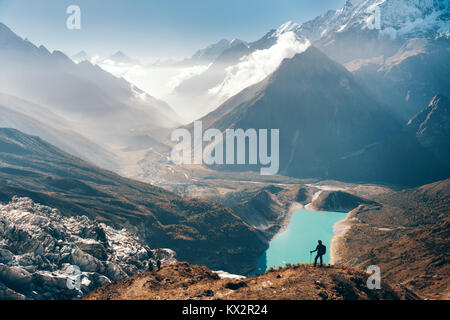 Jeune femme debout sur le sommet de la montagne et à la recherche sur la montagne magnifique vallée avec le lac, rivière et collines au coucher du soleil. Paysage Banque D'Images