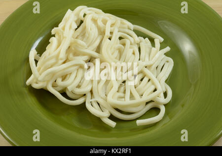 Matières premières fraîches nouilles Udon sur plaque verte comme ingrédient préparé pour faire lo mein lave Banque D'Images