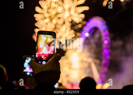 Londres, Royaume-Uni - 1er janvier 2018. Un homme est titulaire d'un téléphone mobile pour enregistrer les feux d'artifice au London Eye pour marquer la fin de 2017. Banque D'Images