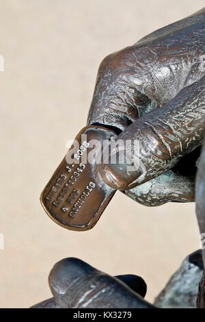 Statue dog tag militaire détenus par la main de personne. Vietnam Memorial, Mobile, Alabama. Mobile et Baldwin comtés, noms de 175 hommes sont sur le mur. Banque D'Images