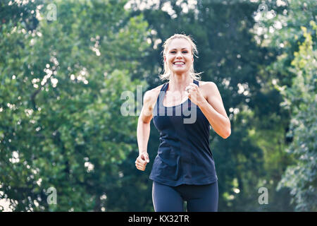 Jeune femme blonde courir dans le parc Banque D'Images