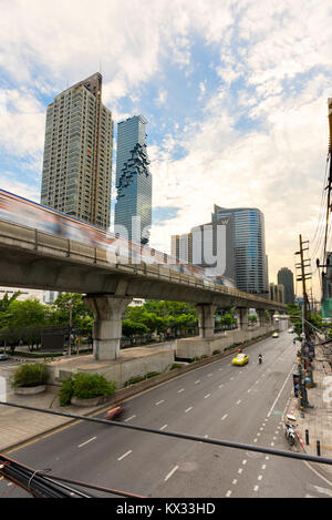 Un mono rail de Bangkok sky train brouille passé sur la route à la construction de gratte-ciel dans le Saint James Silom/Sathon quartier central des affaires de Bangkok, Banque D'Images