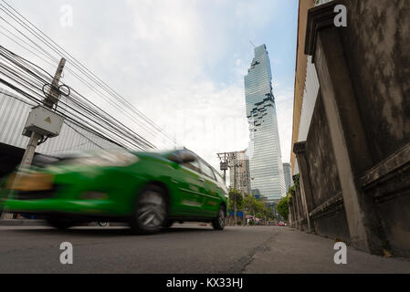 Un taxi vert Bangkok brouille passé sur la route loin de la Saint James immeuble gratte-ciel dans le Silom/Sathon quartier central des affaires de Bangkok, Thail Banque D'Images