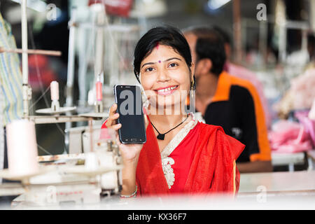 Une femme employée d'usine de couture sur mesure parler de téléphone cellulaire Banque D'Images