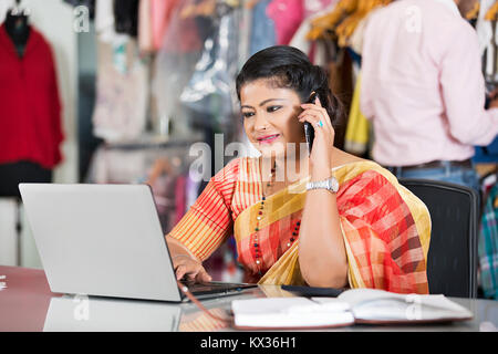 2 Femmes Dress designers Using Laptop travaillant dans la Boutique-Shop Banque D'Images