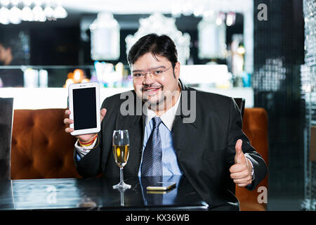 Un homme d'affaires montrant Thumbs-up avec Mobile-Tablet dans Pc- Restaurant Banque D'Images