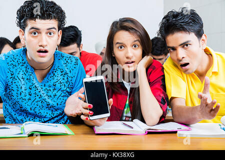 Choqué Indian College étudiants amis montrant Téléphone cellulaire en classe Banque D'Images