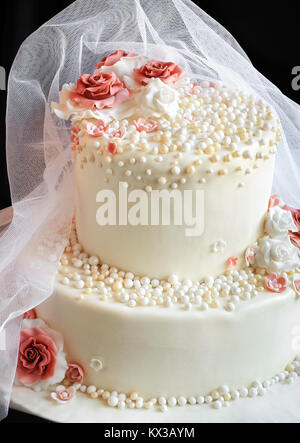 Voile sur le gâteau de mariage avec des roses sur fond noir Banque D'Images