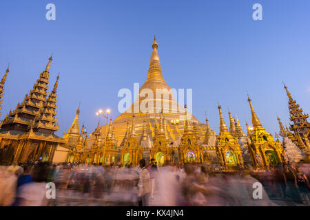 Beaucoup de personnes en face de l'allumé et doré de la pagode Shwedagon à Yangon, Myanmar, à l'aube. Banque D'Images