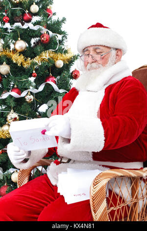 Assis à côté du père Noël arbre de Noël et de la lecture des lettres des enfants pour Noël Banque D'Images