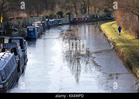 Cheshire, Royaume-Uni Météo. Des températures glaciales la nuit ont laissé une forte frost pour beaucoup au Royaume-Uni. Une personne habillée pour l'hiver comme il court le long de l'toepath sur le Canal de Bridgewater, Warrington avec formé sur la voie d'eau glacée Banque D'Images