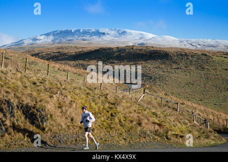 Montagne Plynlimon, Ceredigion Pays de Galles UK, dimanche 07 janvier 2018 UK Weather : un brave jogger court le long de la piste des hautes terres sur un froid glacial , mais croquantes et claires sur les pistes des monts enneigés des montagnes Plynlimon . Les températures ont augmenté à peine au-dessus de zéro tous les jours, et se sentent beaucoup plus froid dans les forts vents de l'est à plus de 750m, Plynlimon est le point le plus élevé au milieu du Pays de Galles. Le nom anglicisé Plynlimon est une forme du mot gallois Pumlumon signifiant 'cinq pics' Photo © Keith Morris / Alamy Live News Banque D'Images