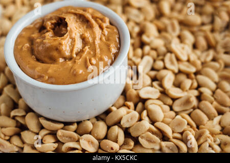 Le beurre d'arachide en pot sur fond d'arachides Banque D'Images