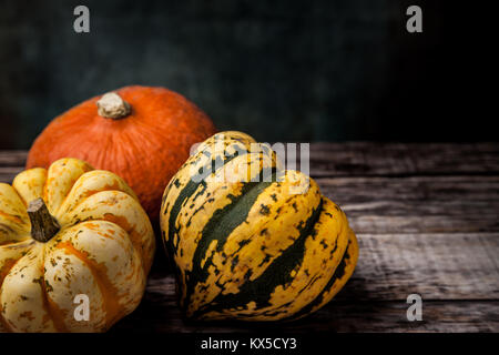 Trois différentes couleurs squash sur table en bois avec fond sombre Banque D'Images