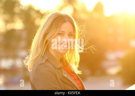 Portrait of a woman smiling and looking at camera au coucher du soleil Banque D'Images