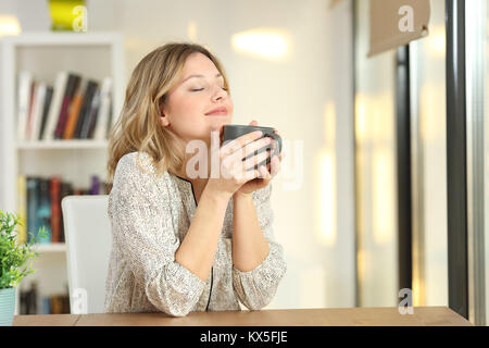 Portrait d'une femme la respiration et la tenue d'une tasse de café à la maison Banque D'Images