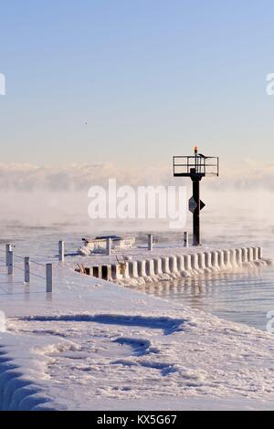 Couches de glace sur un brise-lames que de la vapeur s'élève des eaux du lac Michigan que la glace se forme dans le Chicago's 31st Street Port. Chicago, Illinois, USA. Banque D'Images