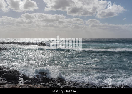 Ein sehr stürmischer Tag à Costa Teguise Lanzarote auf lässt Wellen am Strand brechen. Der Himmel ist wolkenverhangen prasseln und der Regen wird. Banque D'Images