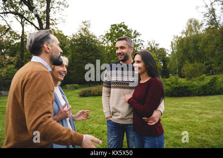 Jeune couple de parler à leurs grands-parents tout en se tenant à l'extérieur Banque D'Images
