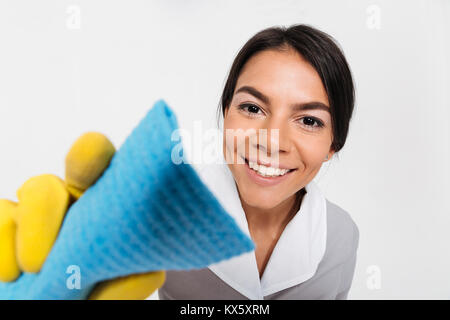 Photo en gros plan de young smiling gouvernante dans des gants de caoutchouc jaune fenêtre de nettoyage avec chiffon, isolé sur fond blanc Banque D'Images