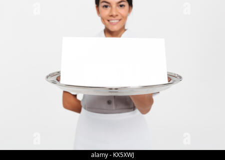 Portrait photo de young female waiter holding tray with metal carte signe vide, selective focus on tray Banque D'Images