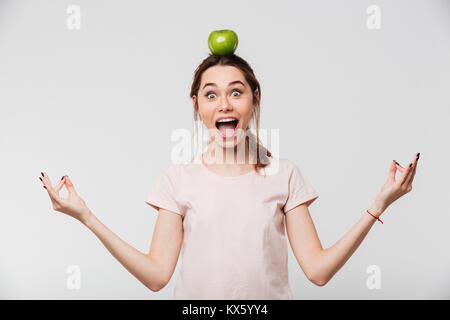 Portrait d'une jolie fille détendue avec une pomme à méditer sur sa tête isolé sur fond blanc Banque D'Images