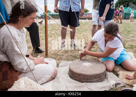 Jeune fille à l'aide d'une meule à main à un site de fouilles archéologiques dans la région de Silchester près de Reading, Berkshire, England, GB, UK Banque D'Images