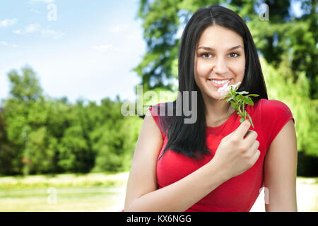 Portrait de belle jeune femme aux cheveux longs en park et fleurs odorantes Banque D'Images