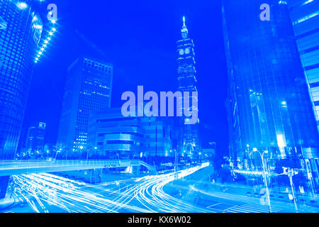 Le blue style light trails de la circulation routière à travers strie une intersection achalandée en face de Taipei 101 Banque D'Images