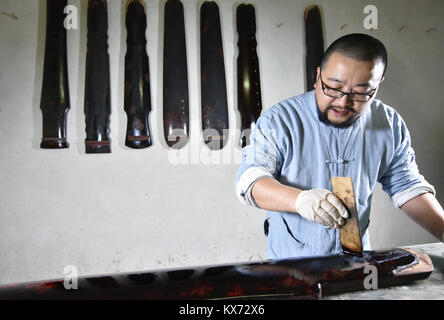 (180108) -- ZUNYI, Janvier 8, 2018 (Xinhua) -- Wang Bing peint un Guqin à Zunyi, au sud-ouest de la province du Guizhou, en Chine, le 7 janvier 2018. Le Guqin chinois, ou cithare chinoise, a une histoire de plus de 3 000 ans et c'est un représentant de la musique chinoise de la tradition. Wang Bing, l'apprentissage de la compétence de guqin à partir de 10 ans, a fait de guqin depuis plus de 30 ans. Il faut plus de 100 procédures de façon parfaite, Guqin selon Wang, l'héritier de prendre des décisions en Guqin Zunyi Ville. Le Guqin faites par Wang est aimé par les fans à la maison et à l'étranger. Guqin et sa musique a été inscrit sur la représen Banque D'Images