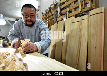 (180108) -- ZUNYI, Janvier 8, 2018 (Xinhua) -- Wang Bing traite un morceau de bois pour la fabrication de guqin Zunyi, au sud-ouest de la province du Guizhou, en Chine, le 7 janvier 2018. Le Guqin chinois, ou cithare chinoise, a une histoire de plus de 3 000 ans et c'est un représentant de la musique chinoise de la tradition. Wang Bing, l'apprentissage de la compétence de guqin à partir de 10 ans, a fait de guqin depuis plus de 30 ans. Il faut plus de 100 procédures de façon parfaite, Guqin selon Wang, l'héritier de prendre des décisions en Guqin Zunyi Ville. Le Guqin faites par Wang est aimé par les fans à la maison et à l'étranger. Guqin et ses musi Banque D'Images