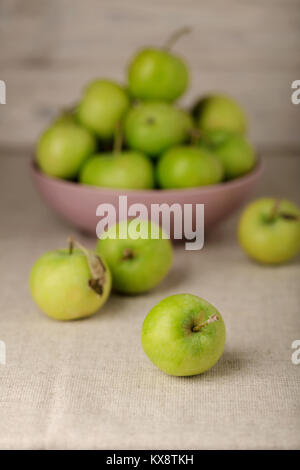 La pomme verte dans une plaque de lilas sur un fond clair en bois. Focus sélectif. Banque D'Images