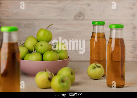 La pomme verte dans une plaque de lilas et une bouteille de jus de pomme en bois sur un fond clair. Focus sélectif. Banque D'Images