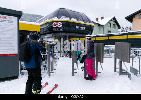 Skieurs et planchistes passer par tourniquets tripodes portes et télésiège d'embarquement en direction du sommet de Skrzyczne mountain à Szczyrk en Pologne Banque D'Images