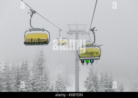 Télésiège de ski réunissant les skieurs et les surfeurs de la montagne Skrzyczne après les fortes chutes de neige sur une journée d'hiver brumeux de ski à Szczyrk en Pologne Banque D'Images