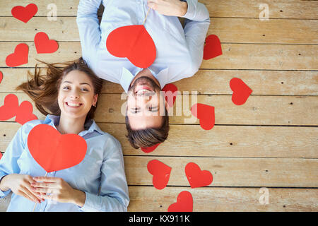 Couple allongé sur le plancher en bois avec des coeurs Vue de dessus. Banque D'Images