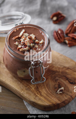 Close-up de la mousse au chocolat dans le bocal en verre avec des noix de pécan. Banque D'Images