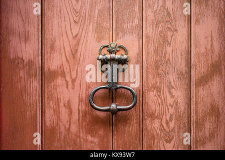 Vue frontale d'un heurtoir de porte en fonte vintage monté sur une vieille porte en bois. Banque D'Images