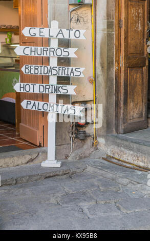 Fun signer avec la flèche formes et éléments de menu écrit sur eux, sur une pierre ronde, en face d'un gelato local shop, à Guanajuato, Mexique Banque D'Images