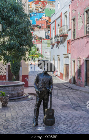 Statue sur la Plaza del Ropero, décoration avec chaussée de pierre, et une rue étroite à la tête de maisons colorées qui parsèment la colline, à Guanajuato Banque D'Images