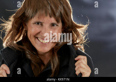Belle femme d'âge moyen avec des cheveux bruns en couches smiling avec éclairage arrière Banque D'Images