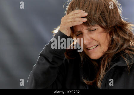 Femme d'âge moyen avec les yeux fermés et sa main sur son front avec éclairage arrière Banque D'Images
