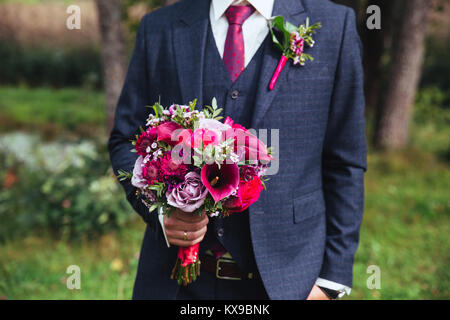 Le marié élégant en costume et nœud papillon avec bouquet . Banque D'Images