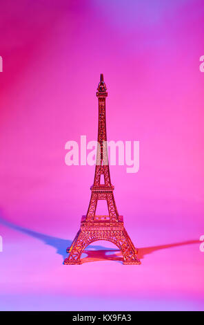 Une statuette en or de la Tour Eiffel illuminée de deux côtés de la lumière rouge et bleu Banque D'Images