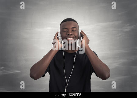 Happy african man smiling écouter de la musique dans le casque. Fond gris. Banque D'Images