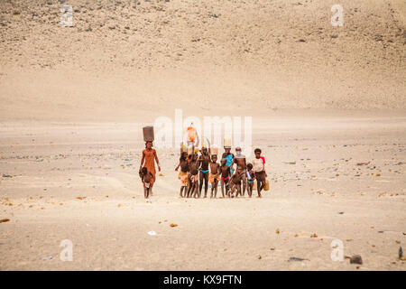 Femme Himba et les enfants travaillant au transport de l'eau pour un village de tribu Himba peuple autochtone de la région de Kunene, le nord de la Namibie, l'Afrique du Sud-Ouest Banque D'Images