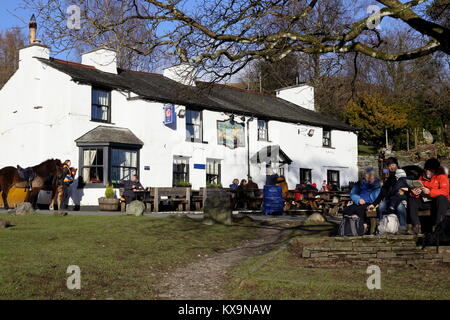 Les visiteurs apprécient un dimanche ensoleillé en janvier à l'extérieur de la Britannia Inn at Lake Road dans le Parc National de Lake District, Cumbria. Banque D'Images