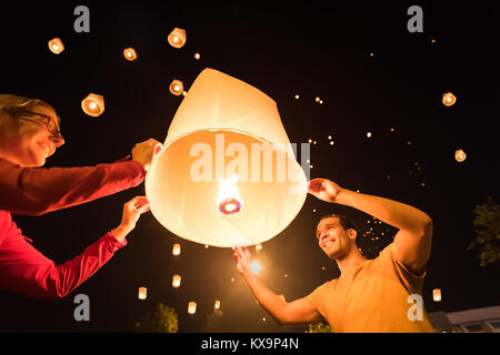 Deux personnes libérant une lanterne volante traditionnels à Yi Peng / Loy Krathong festival à Chiang Mai, Thaïlande Banque D'Images
