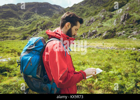 Hiker using digital tablet sur le paysage de campagne Banque D'Images